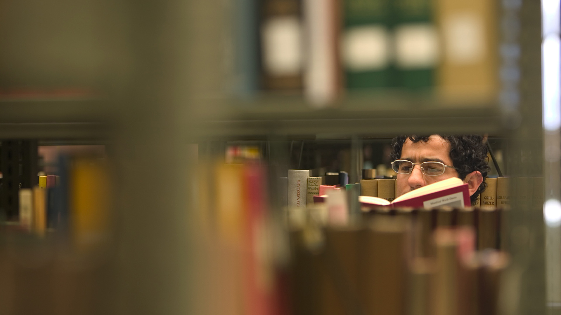 Man reading book in library stacks